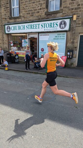 Side view of Emily Green running in the Eyam Half Marrathon, near the end of the race.