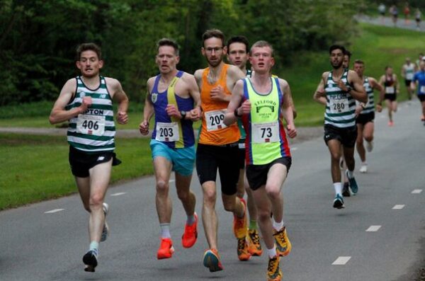 Several runners running flat out along a tarmac track