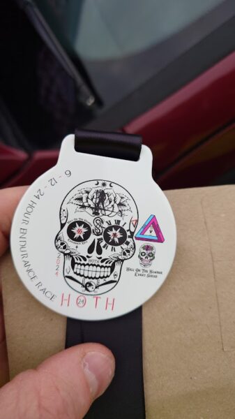 A race medal, showing a Day of the Dead-style skull and the words "6-12-24 hour endurance race HOTH 24"